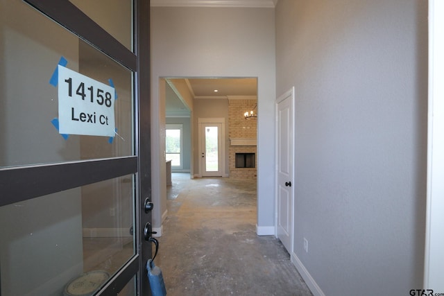 hall with concrete flooring, a notable chandelier, and ornamental molding