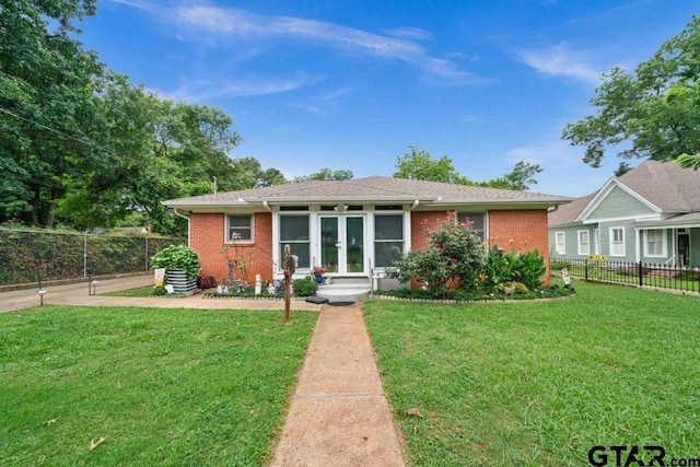 view of front of house with brick siding, a front lawn, fence, and french doors