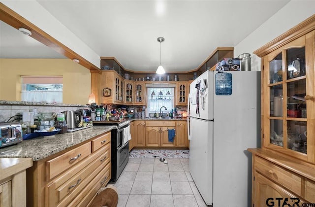 kitchen featuring freestanding refrigerator, glass insert cabinets, range with two ovens, a sink, and backsplash