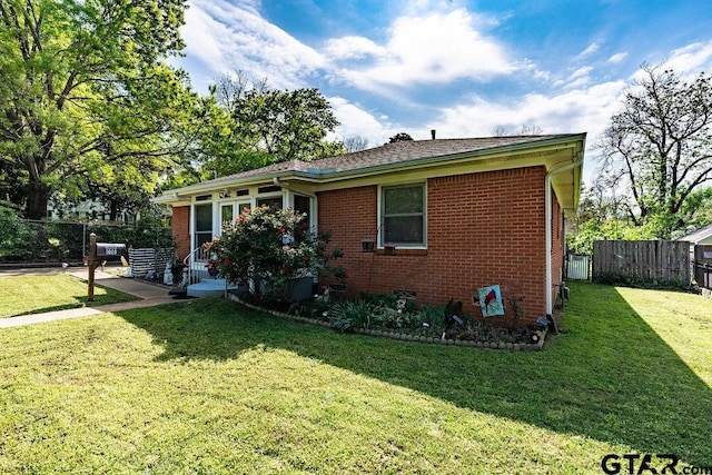 view of front of home featuring brick siding, fence, a patio, and a front yard