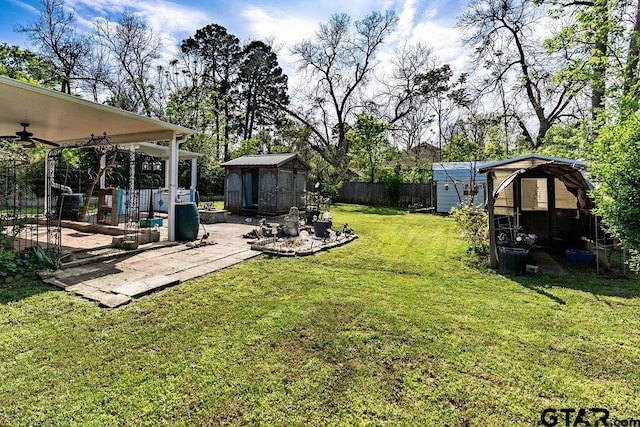 view of yard featuring an outdoor structure, a patio area, fence, and a storage shed