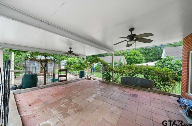 view of patio / terrace with an outdoor structure, a ceiling fan, a shed, and fence