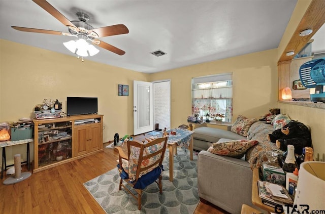 living room with visible vents, ceiling fan, and light wood-type flooring