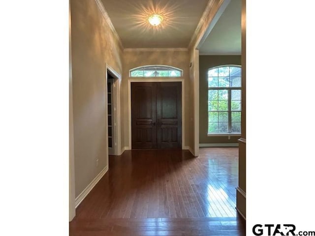 entryway featuring hardwood / wood-style flooring, ornamental molding, and baseboards