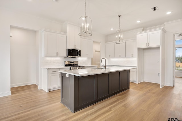 kitchen featuring white cabinetry, stainless steel appliances, and an island with sink