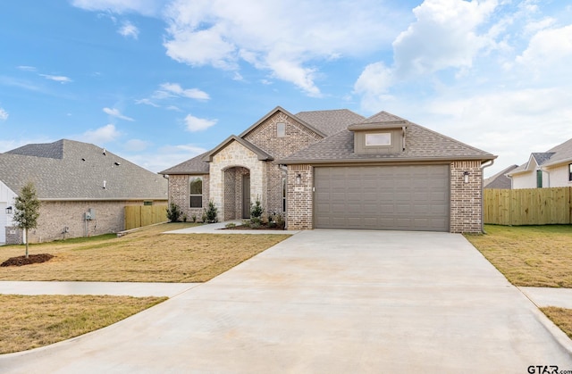 french country style house featuring a garage and a front lawn