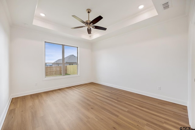 unfurnished room featuring a tray ceiling, ceiling fan, light hardwood / wood-style flooring, and crown molding