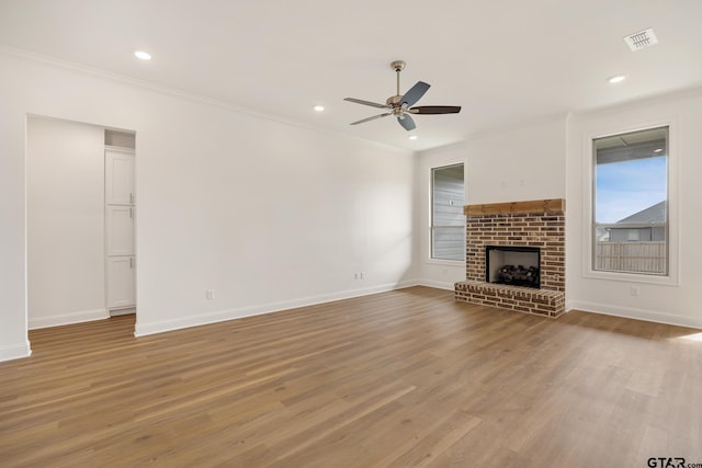 unfurnished living room with ceiling fan, light hardwood / wood-style floors, ornamental molding, and a fireplace