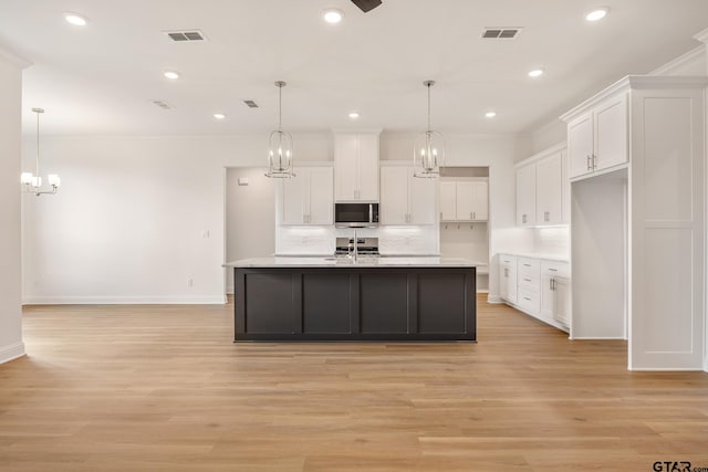 kitchen featuring white cabinetry, hanging light fixtures, and appliances with stainless steel finishes