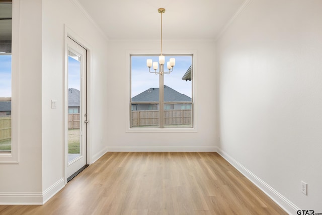 unfurnished dining area with a notable chandelier, light wood-type flooring, and crown molding