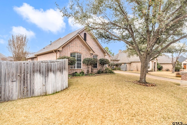 exterior space with brick siding, a lawn, and fence