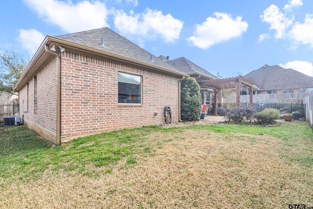 back of house with a yard, brick siding, a pergola, and central AC