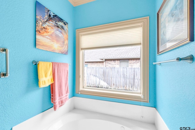 bathroom featuring a garden tub and a textured wall