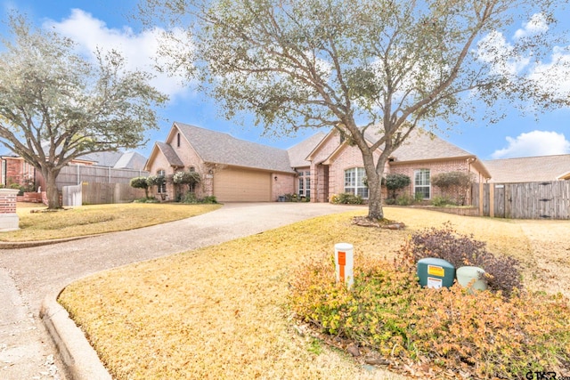 view of front of house with brick siding, an attached garage, concrete driveway, and fence