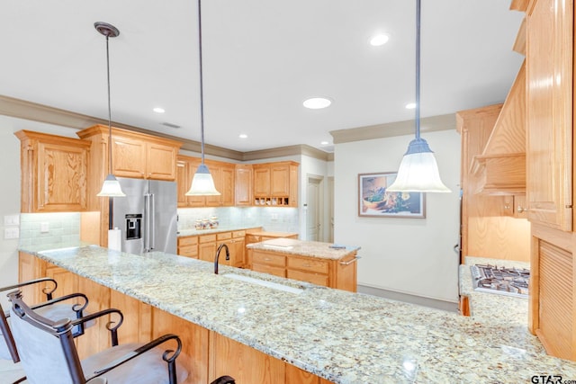 kitchen featuring light stone countertops, light brown cabinetry, decorative backsplash, appliances with stainless steel finishes, and a sink