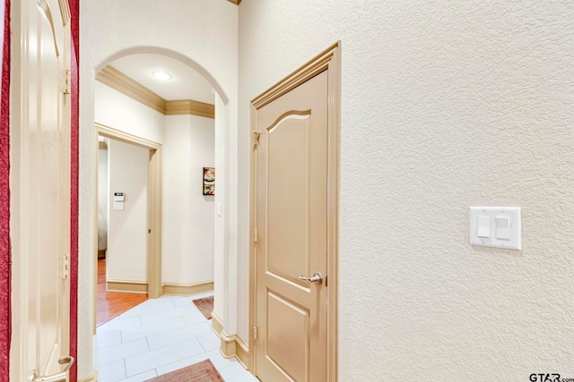 hall with light tile patterned floors, a textured wall, and arched walkways