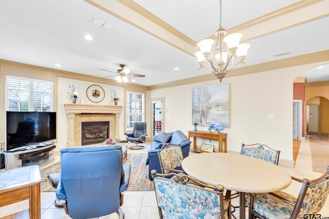 living area featuring visible vents, a fireplace, arched walkways, crown molding, and ceiling fan with notable chandelier