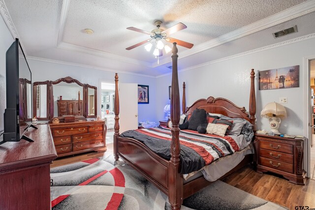 1511 Dolly Ln, Hideaway, TX 75771 - bedroom with wood finished floors, a raised ceiling, a textured ceiling, ornamental molding, and a ceiling fan