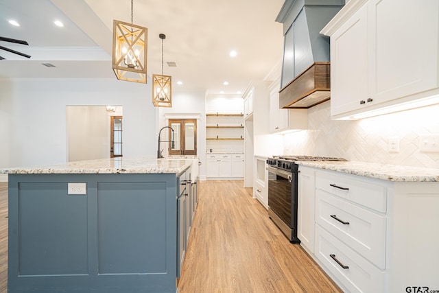 kitchen with hanging light fixtures, a spacious island, gas range, and white cabinetry