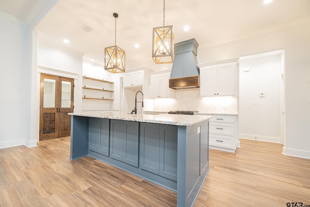 kitchen with white cabinetry, hanging light fixtures, a sink, and custom exhaust hood