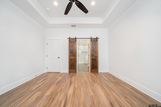 unfurnished bedroom featuring light wood-type flooring, a raised ceiling, visible vents, and crown molding