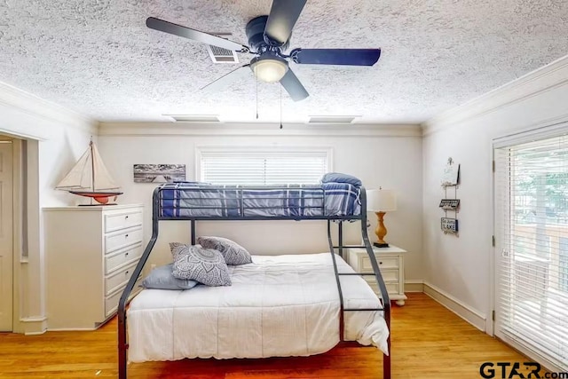 bedroom with a textured ceiling, light wood-type flooring, and crown molding