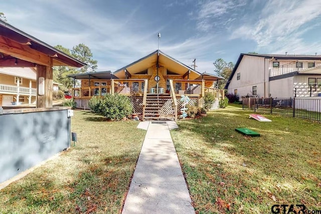 exterior space with a deck, stairway, a front yard, and fence