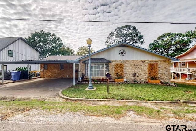 single story home with a carport, brick siding, and a front lawn