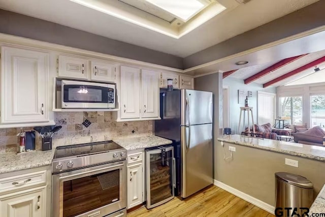 kitchen featuring decorative backsplash, appliances with stainless steel finishes, light wood-style floors, white cabinets, and beverage cooler