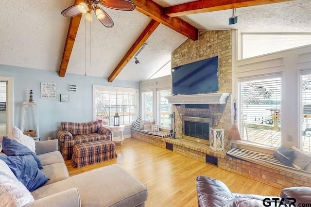 living area with a fireplace, visible vents, a textured ceiling, and wood finished floors