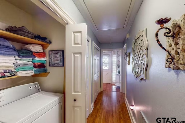 corridor with baseboards, wood finished floors, washer / dryer, and attic access