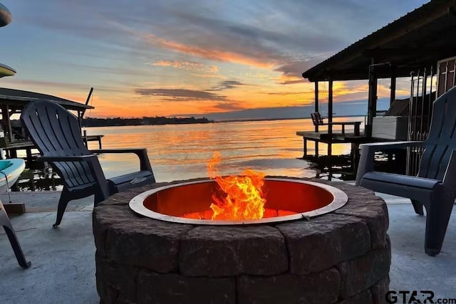 patio terrace at dusk with a fire pit and a water view