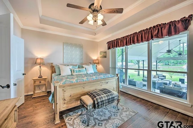 bedroom with dark wood-type flooring, ornamental molding, ceiling fan, and a raised ceiling