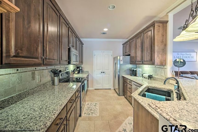 kitchen featuring stainless steel appliances, sink, light stone counters, and decorative backsplash