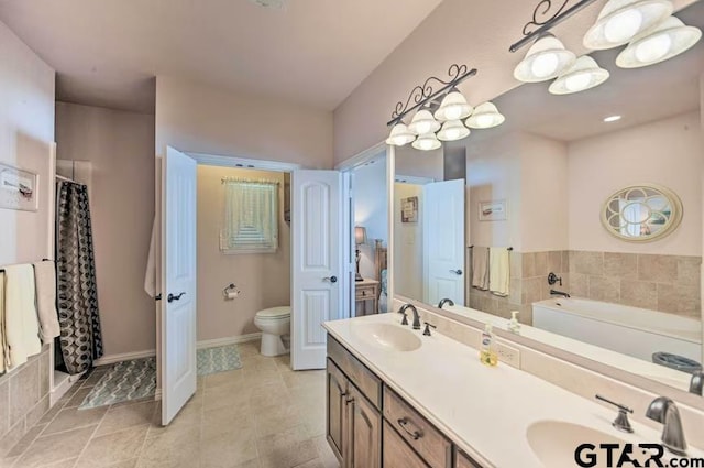 bathroom with a washtub, vanity, and toilet