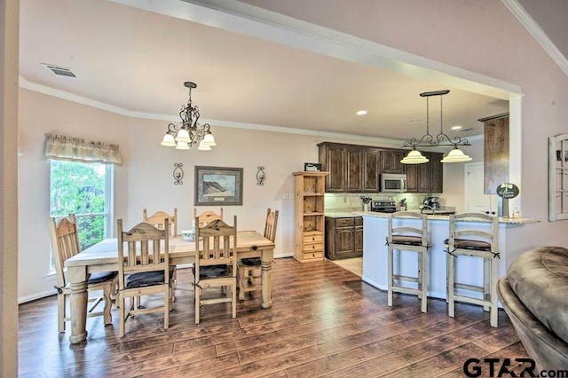 dining space featuring dark wood-type flooring, crown molding, and a notable chandelier