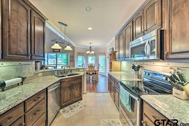 kitchen featuring stainless steel appliances, sink, tasteful backsplash, light stone countertops, and pendant lighting