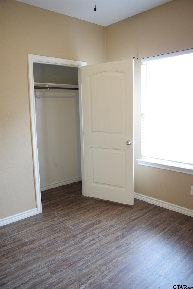 unfurnished bedroom with dark hardwood / wood-style flooring and a closet