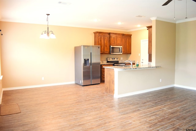 kitchen with stainless steel appliances, light hardwood / wood-style floors, kitchen peninsula, hanging light fixtures, and light stone countertops