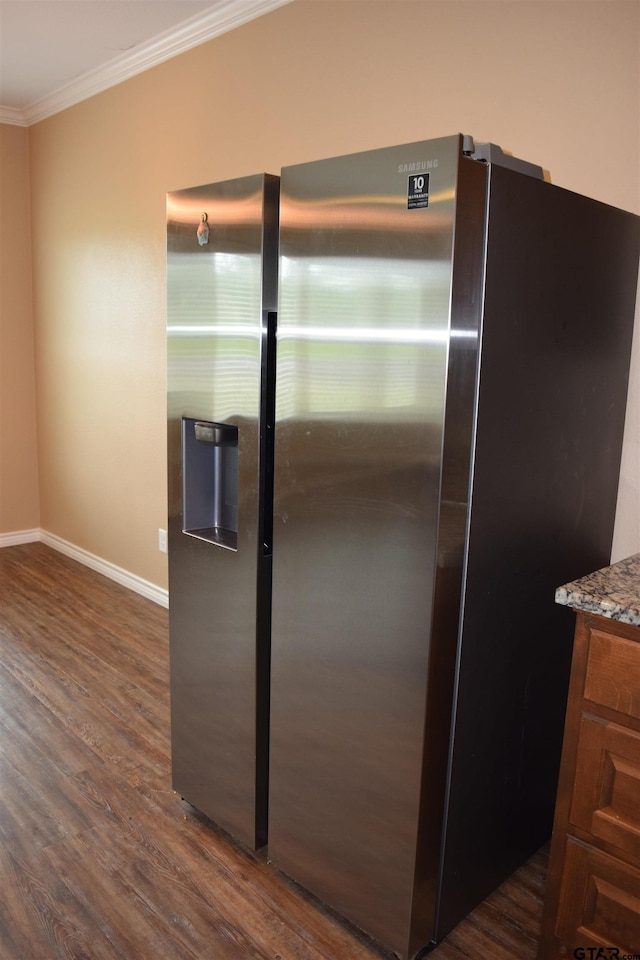 kitchen with stone countertops, stainless steel fridge, dark hardwood / wood-style floors, and crown molding