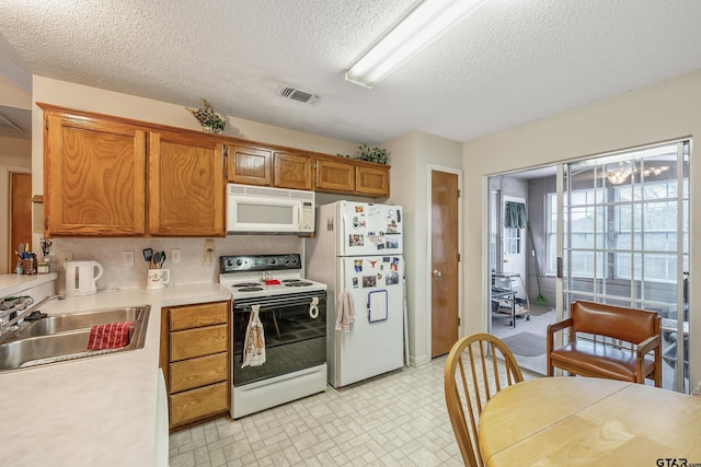 kitchen featuring white appliances, visible vents, brown cabinets, light countertops, and a sink