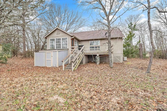 rear view of house with an outbuilding, stairway, and a wooden deck