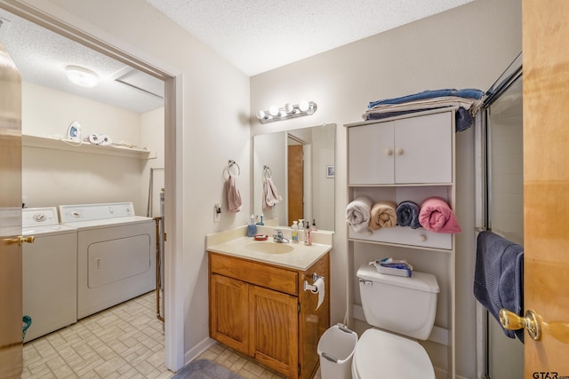 bathroom with vanity, washer and clothes dryer, toilet, and a textured ceiling