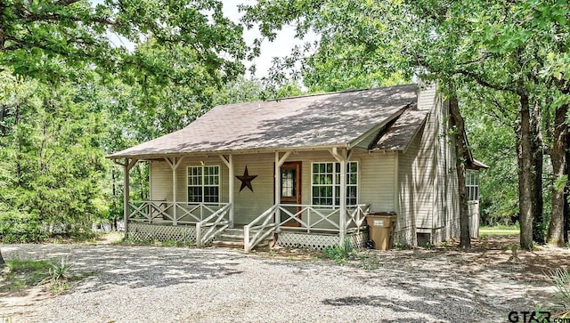 207 Pagosa Ln, Holly Lake Ranch, TX 75765 - view of front facade with covered porch, a chimney, and roof with shingles