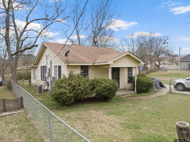 bungalow with central air condition unit, fence, a front lawn, and roof with shingles