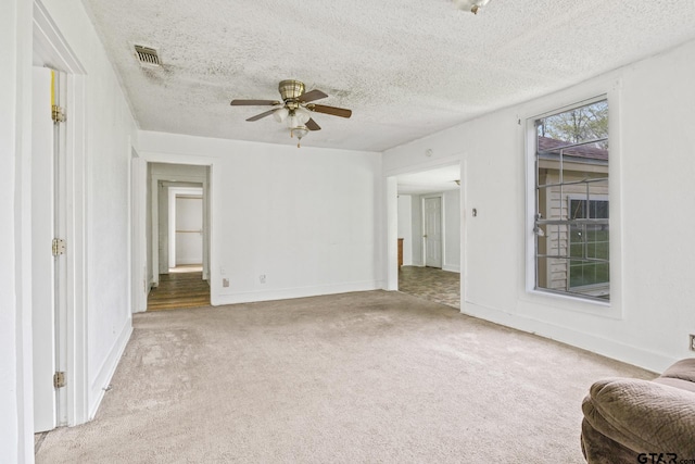 unfurnished living room featuring carpet flooring, a textured ceiling, baseboards, visible vents, and ceiling fan