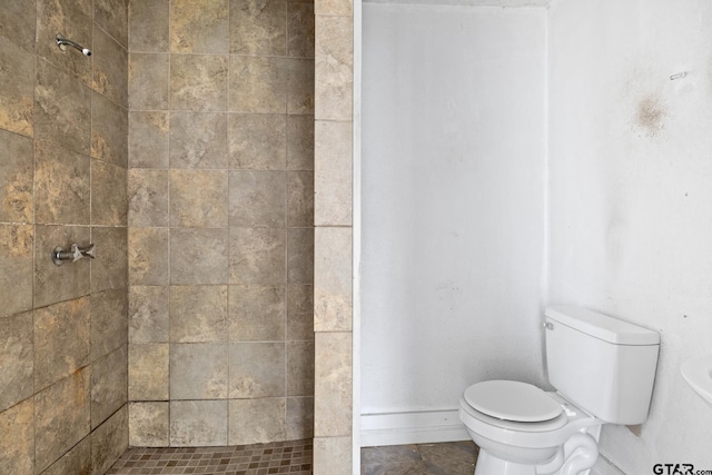 bathroom featuring toilet, baseboards, and tiled shower