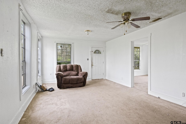 living area featuring a textured ceiling, visible vents, carpet, and plenty of natural light