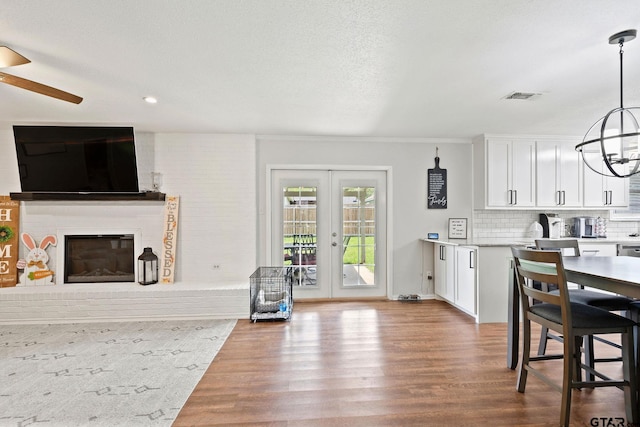 kitchen featuring white cabinets, open floor plan, wood finished floors, and ceiling fan with notable chandelier