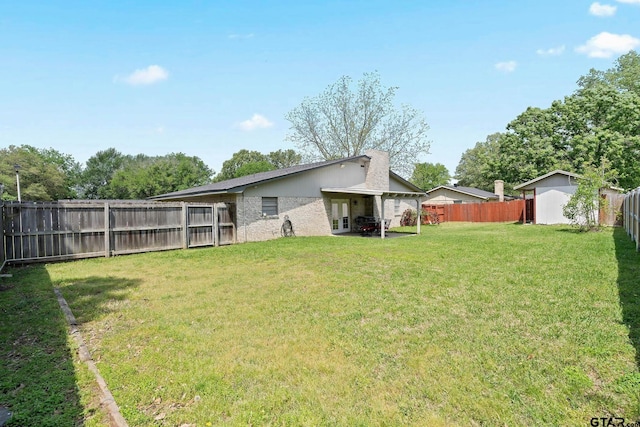 rear view of property with a lawn, a fenced backyard, and french doors